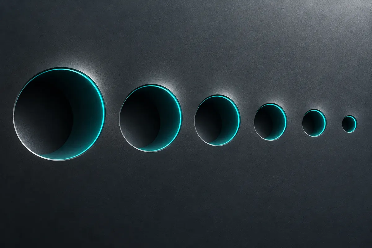 A smooth graphite surface with a row of round openings that become smaller from left to right, each rim lit in teal